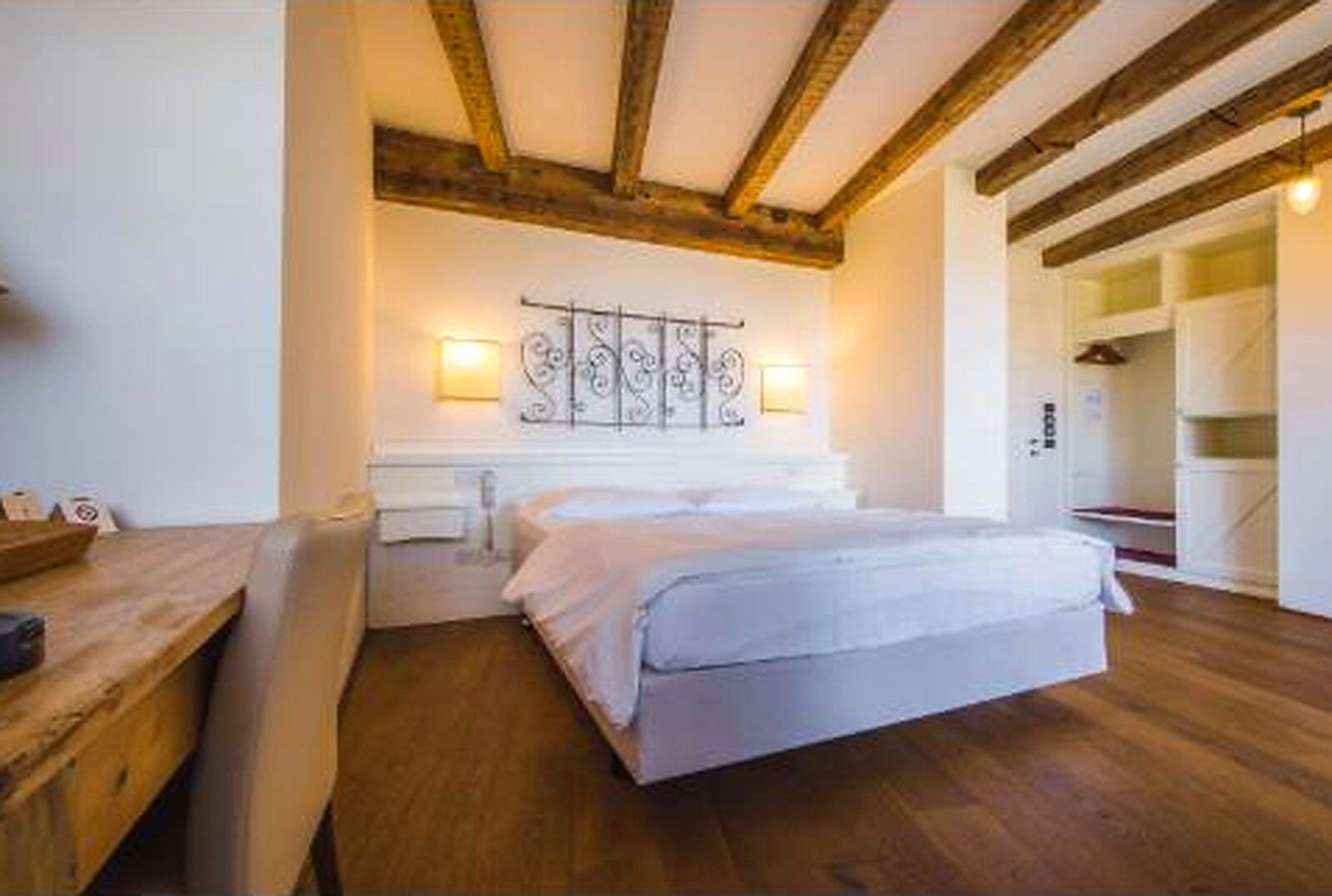 Camera del Relais Vecchio Maso con travi in legno e testiera in ferro battuto